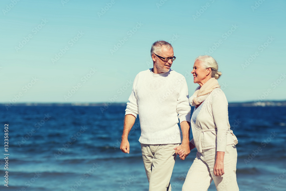 Wall mural happy senior couple holding hands on summer beach