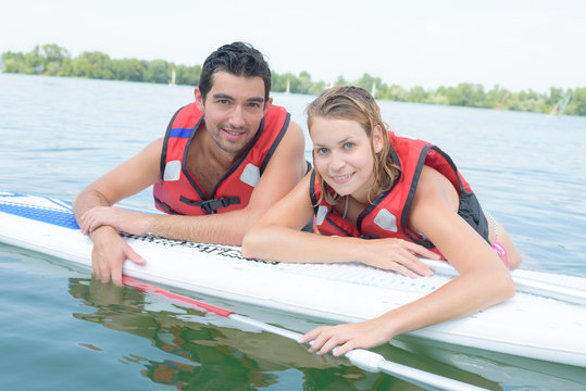 young couple swiming with paddle board in a lake