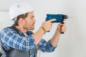 young handsome handyman using a drill at work