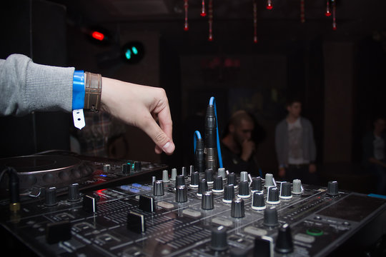 DJ hand on equipment in a nightclub