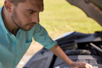 man with open hood of broken car at countryside