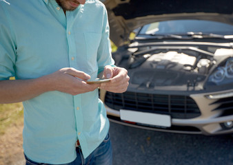 close up of man with smartphone and broken car