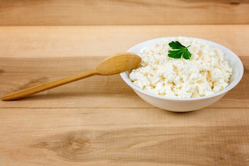 Fresh cottage cheese in a white bowl with spoon