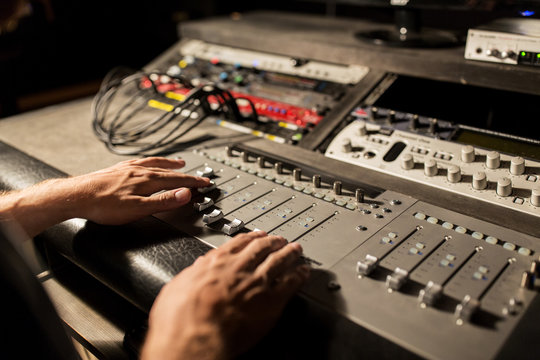 man using mixing console in music recording studio