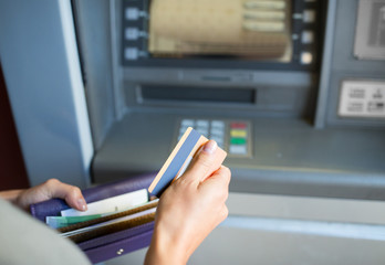 hands with money and credit card at atm machine