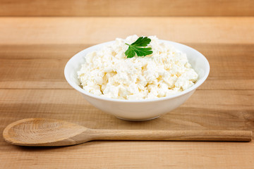 Fresh cottage cheese in a white bowl with spoon