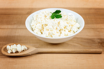 Fresh cottage cheese in a white bowl with spoon