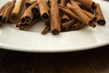 Cinnamon Sticks And White Plate On Wood Tabletop, Close
