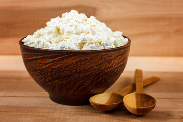 Fresh cottage cheese in bowl on a wooden