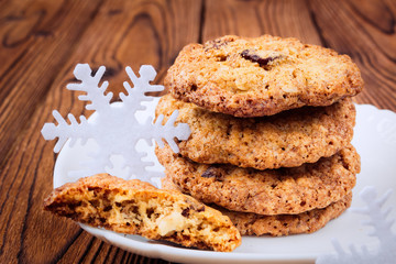 Oat cookies with raisins and nuts on a brown wooden table with C
