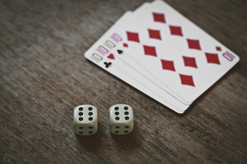 four tens on a wooden table. concept of gambling and place for your text. playing cards and two dice number double six closeup.