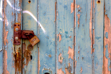 Blue wooden door with flaking paint and rusty lock