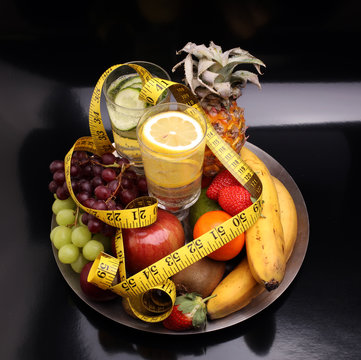 fitness equipment and healthy food and detox water (green apple, pepper, grapes, nectarines, kiwi, orange, dumbbells and measuring tape) 