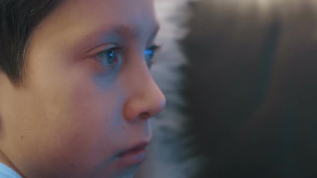 Young boy watching TV at home ultra colse up