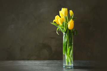 Glass vase with bouquet of beautiful tulips on color background