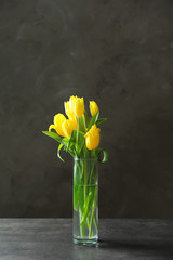 Glass vase with bouquet of beautiful tulips on color background