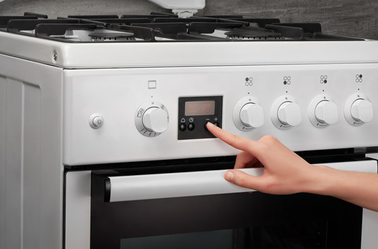 Female hand turning on white kitchen gas stove