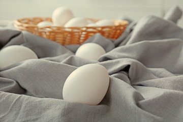 Fototapeta na wymiar Raw eggs in wicker basket on tablecloth