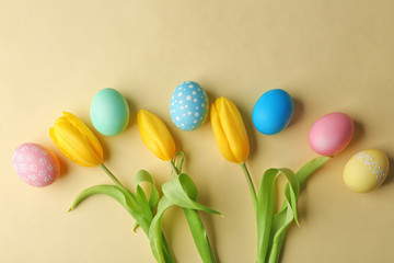 Fototapeta na wymiar Colourful Easter eggs and flowers on beige background
