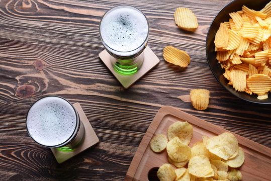 St. Patrick Day concept. Glasses of green beer and crisps on wooden table