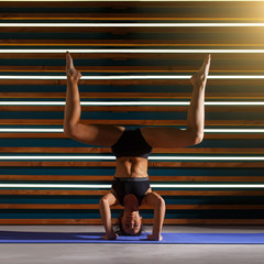 Young woman doing yoga exercises in dark studio. Health lifestyle concept.