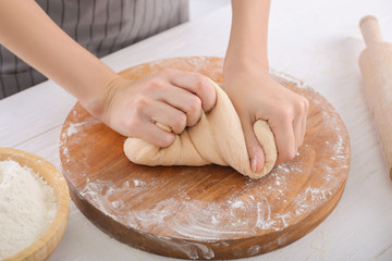 Obraz na płótnie Canvas Woman kneading dough on kitchen table, closeup