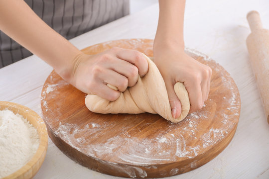 Woman kneading dough on kitchen table, closeup