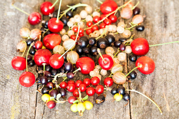 Currants, cherries and other summer fruits with old wood texture
