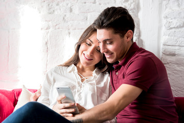 Happy young couple relaxed at home with mobile phone