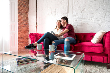 Happy young couple relaxed at home with mobile phone