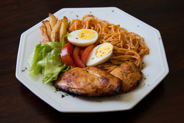 Food dish with grilled chicken, pasta, eggs, lettuce, tomato and french fries