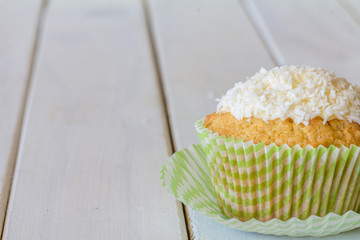Close Up of Snowball Cupcake with Copy Space Left on White Wooden Table with Selective Focus Horizontal