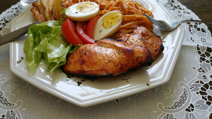 Food dish with grilled chicken, pasta, lettuce, egg, tomato and french fries