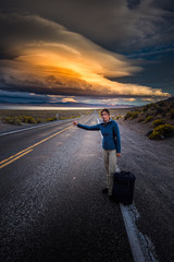 Obraz na płótnie Canvas Hitchhiking on a desert road at sunset