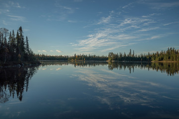 Fototapeta premium Still Northern Ontario lake in early morning with reflected clou