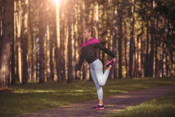 Fit girl are stretching in woods.