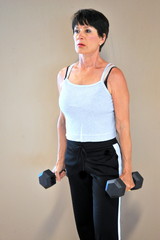 Mature female beauty working out with hand barbells.