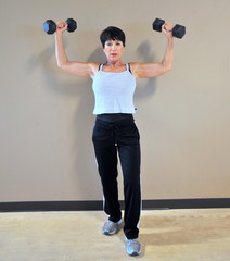 Mature female beauty working out with hand barbells.