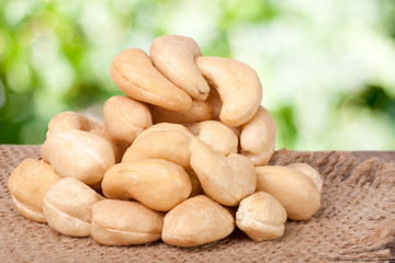heap of cashew nuts on a wooden table with sacking and blurred garden background