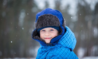 Happy little boy playing outdoor in winter snow