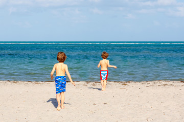 Two little kids boys having fun on tropical beach