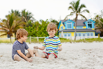 Two kid boys building sand castle on tropical beach