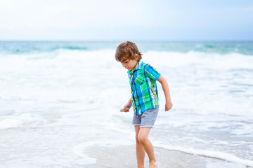 Fototapeta na wymiar little kid boy running on the beach of ocean