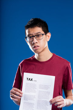 doubtful asian man holding a tax form