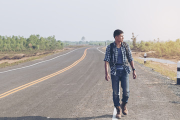 Man standing beside the road hitchhiking. Backpackers