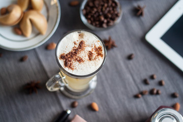 Latte with fortune cookies on a gray tablecloth near ipad