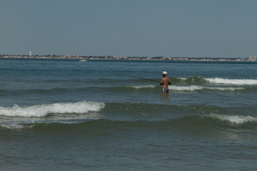 Fototapeta na wymiar A retired fisherman in the water on the beach