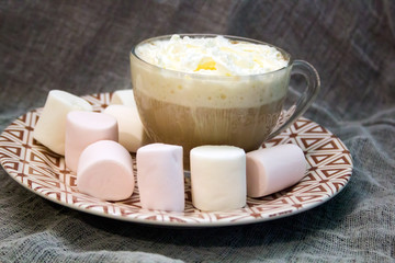 creamy cappuccino in a glass mug and marshmallows