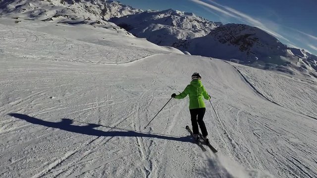 Slow motion: Young woman is skiing down on slope on sunny day, Tignes, France