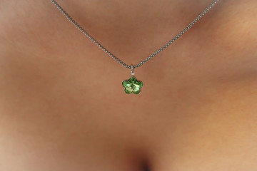 Beautiful silver necklace with green malachite gem. Jewellery on the neck of girl. Women breast in background
